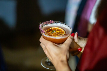 Elegant Cocktail with Dried Orange Garnish in Hand