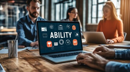 A laptop screen displays the word 'ABILITY' with various icons on a desk in an office.