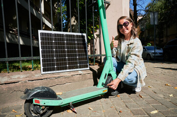 Woman connecting solar panel to electric scooter, highlighting practical application of sustainable...