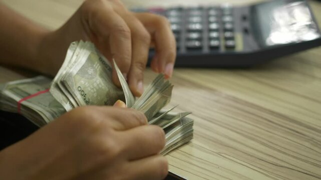 Closeup of hand counting 500 Indian rupee banknotes at a store