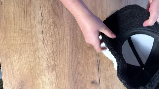 A woman is examining white and black fur caps. She is reviewing the purchase. Showcasing the design elements. Vertical video.