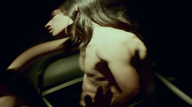 Long-haired man with bare torso moving slowly in dimly lit room, his reflection stretching and warping in distorting mirror, creating ethereal and surreal atmosphere