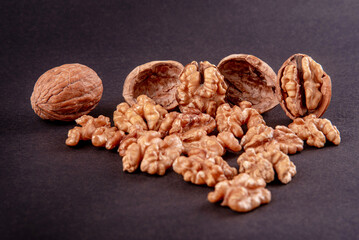 Four whole walnuts in the shell laid out in a row on a black background