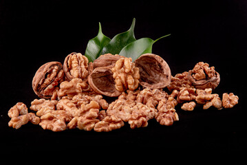 Four whole walnuts in the shell laid out in a row on a black background