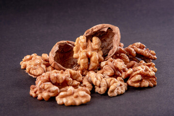 Four whole walnuts in the shell laid out in a row on a black background