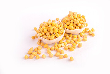 Dried chickpeas in white bowl on white. Spilled chickpeas.
