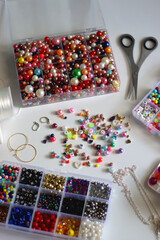 Colorful beads, letter beads, threads and other jewelry making supplies on white background. Making friendship bracelets concept. Selective focus.