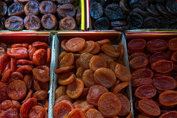 Orange and dark dried apricots in boxes for sale at the market, top view. Dried fruit, dried apricots as background.