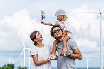 Happy cheerful caucasian white family with daughter are walking and playing toy windmill together...