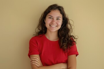 Obraz premium A woman wearing a red shirt stands with her arms crossed, appearing confident and assertive