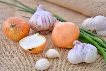 Yellow and green onions, garlic on jute. Vitamins during colds.