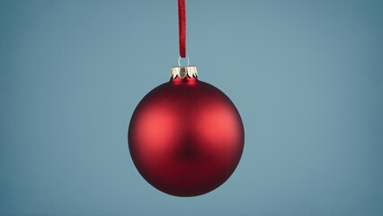Red Christmas bauble hangs from red ribbon against a blue background