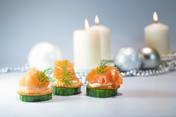 Festive finger food canapes from smoked salmon, cucumber and crackers with dill garnish, candles...