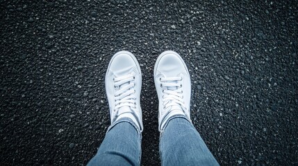 Defocused cropped view of white sneakers on an asphalt background with feet and legs visible from above Ideal for various creative applications
