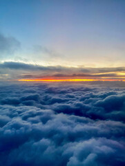Sunset above the clouds, view from the window of an airplane