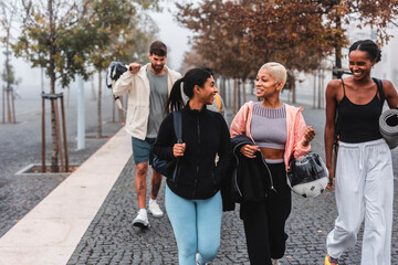 Naklejka premium Group of sporty friends walking together in the city after training