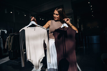 Illuminated by sunlight, darkened. Woman chooses clothes in retail store