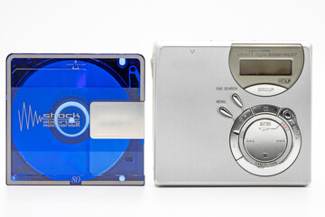 Close-up of a minidisc player and recorder next to a minidisc disc isolated on white background