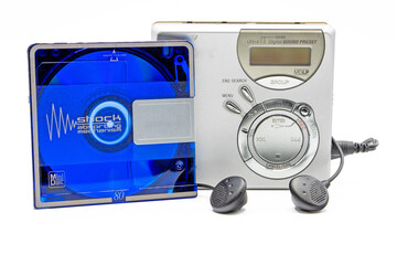 close-up of a minidisc player and recorder with headphones next to a minidisc record isolated on white background