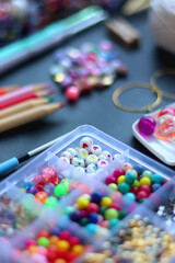 Colorful beads, coloring pencils, glitter, needles, string, hoop, tape and scissors on dark...
