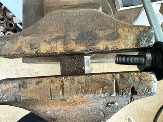 Close-up of an industrial vise clamping a metal bolt