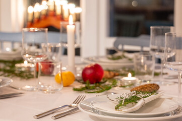 Festively decorated dinner table set for a Christmas celebration, with lit candles, fresh greenery, and seasonal decorations, exuding a warm and inviting holiday ambiance