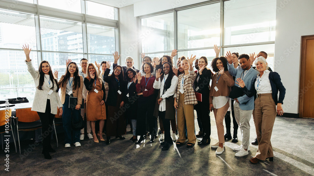 Wall mural diverse group at seminar happily waving inside modern conference room with large windows and bright 