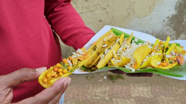 Man eating boti masala chaat or crunchy fryums with salad, chutneys, puffed rice, sev