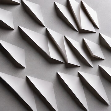 Fototapeta Abstract arrangement of white paper shapes forming geometric patterns on a flat surface, creating an interplay of light and shadow across sharp edges