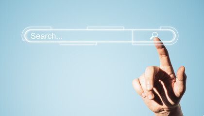 Close up of man hand pointing at glowing search bar on blue background.