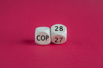 Symbol for the next climate conference. Turned a wooden cube and changes the expression 'COP27' to 'COP28'. Beautiful red background