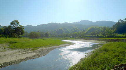 Obraz premium A serene river winding through a lush green valley with rolling hills in the background.