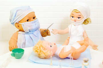 Toy doctor and doll nurse under treatment of sick little doll