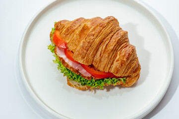 croissants stuffed with ham and vegetables on a white background