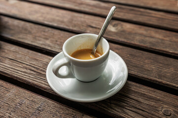 tazzina piena di caffè espresso, di giorno, dopo pranzo, su un tavolo di legno, all'aperto