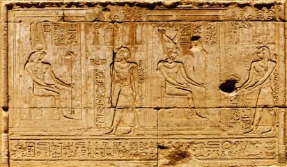 Ancient Egyptian relief features detailed carvings of figures and hieroglyphics on a stone...