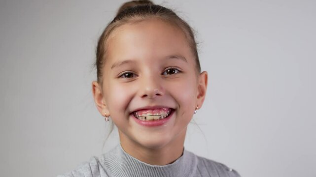 Girl with dental braces or teeth retainers for teeth correction. Pretty girl wearing braces smiling, looking at camera, close-up.