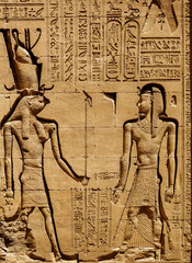 Ancient Egyptian relief features detailed carvings of figures and hieroglyphics on a stone...