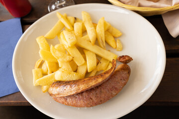 piatto bianco con patate fritte e una salsiccia, a pranzo