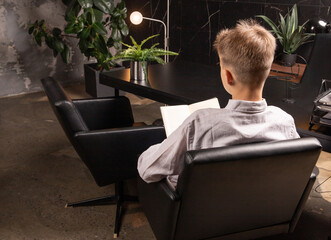 A thoughtfully designed workspace features a young person seated, engrossed in a book. Lush green...