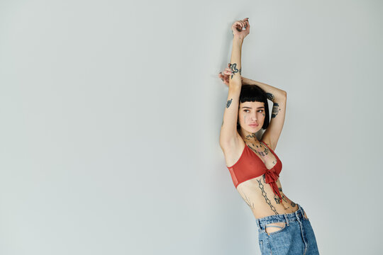 A stylish tattooed woman strikes a pose in trendy attire.
