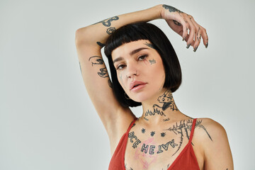A fashionable woman showcases her tattoos with a confident pose.