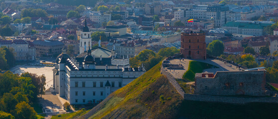 Obraz premium Aerial view of Vilnius, Lithuania, featuring Gediminas' Tower on a hill with the Lithuanian flag. Vilnius Cathedral and bell tower are visible nearby.