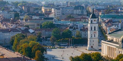 Aerial view of Vilnius, Lithuania, featuring the Vilnius Cathedral Bell Tower with its white facade and black spire, surrounded by a spacious square and cityscape.