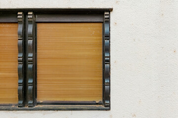 A window with wooden blinds is closed and framed in black trim