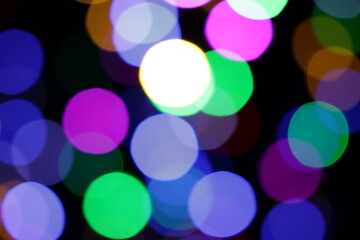 Una toma de cerca de una fondo abstracto de luces de navidad de diferentes colores en la oscuridad. Desenfoque bokeh