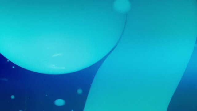 Blue lava bubbles flowing in liquid against dark background. Slow motion, abstract. 