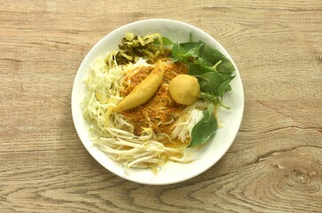 rice noodles dressing spicy fish curry sauce eat couple fresh vegetable on plate