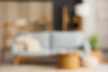 Interior of modern living room with grey sofa, shelving units and coffee table, blurred view