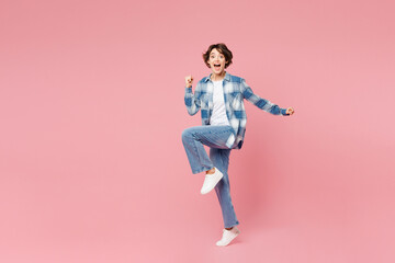 Full body young woman she wears blue shirt white t-shirt casual clothes doing winner gesture celebrate clenching fists raise up leg isolated on plain pastel light pink background. Lifestyle concept.